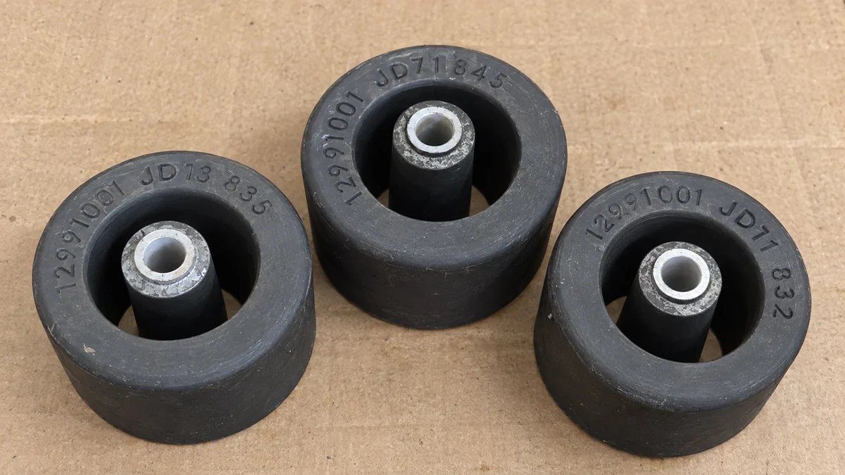 Three black components with metal inner sleeves on a cardboard surface