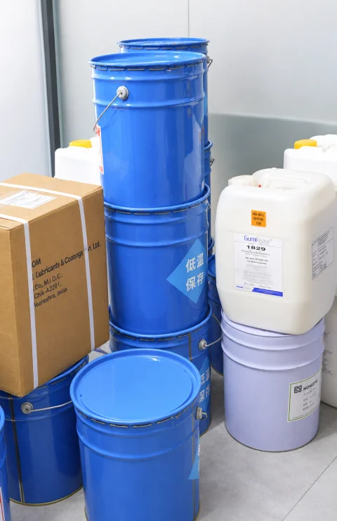 Blue industrial drums and a cardboard carton arranged indoors